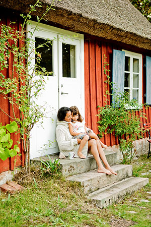Mutter mit Kind vor ihrem Ferienhaus in Schweden